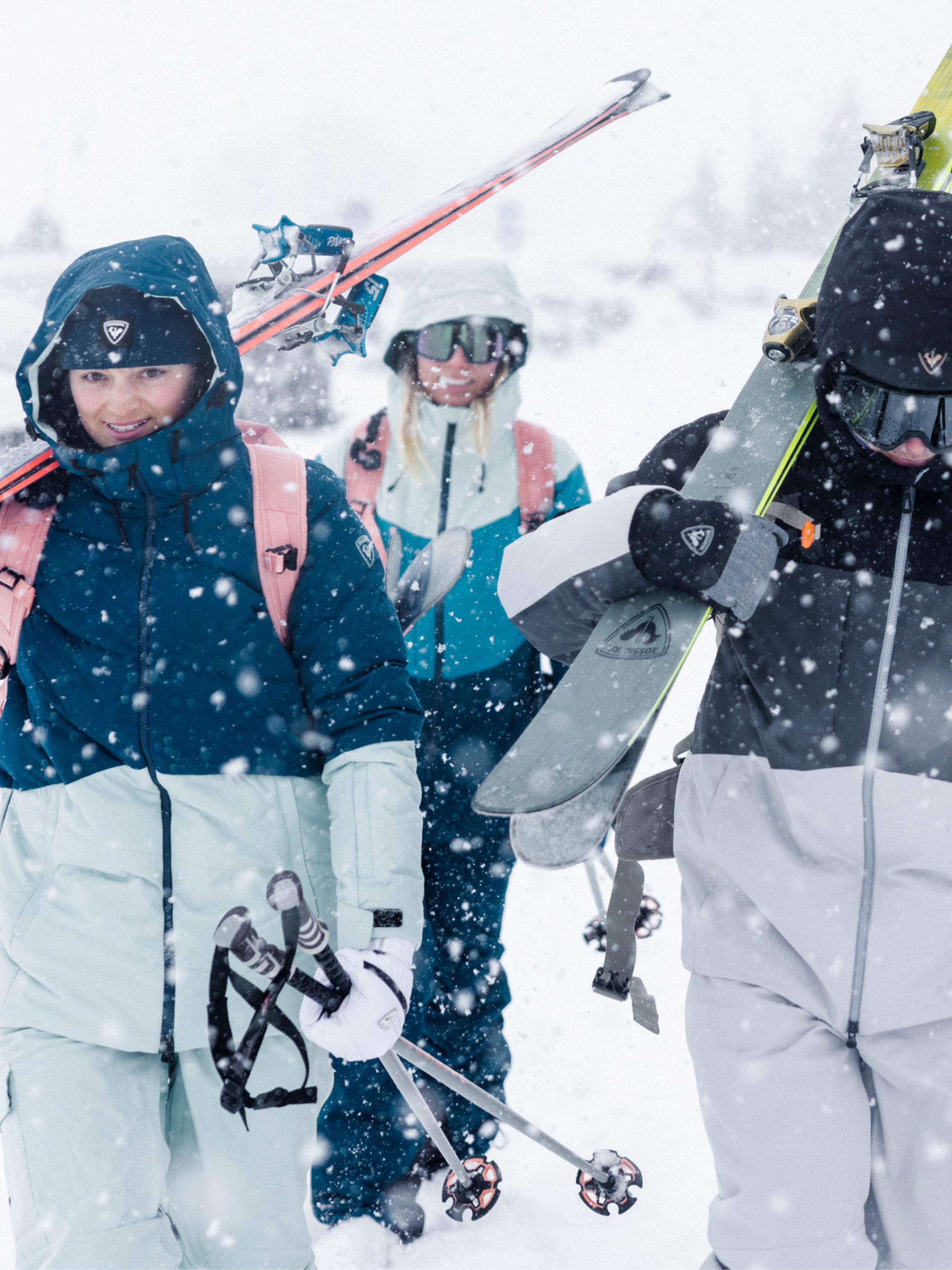 Skiers and snowboarders trekking through flurries.