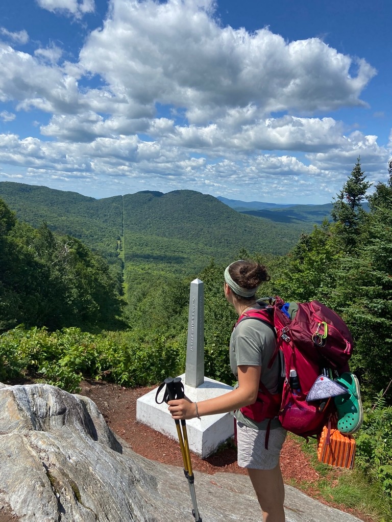 A hiker stands at the northern terminus of the Long Trail