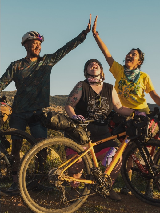 Mountain bikers laugh and high-five while taking a break.