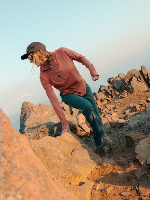 A hiker scrambles up a rocky summit.