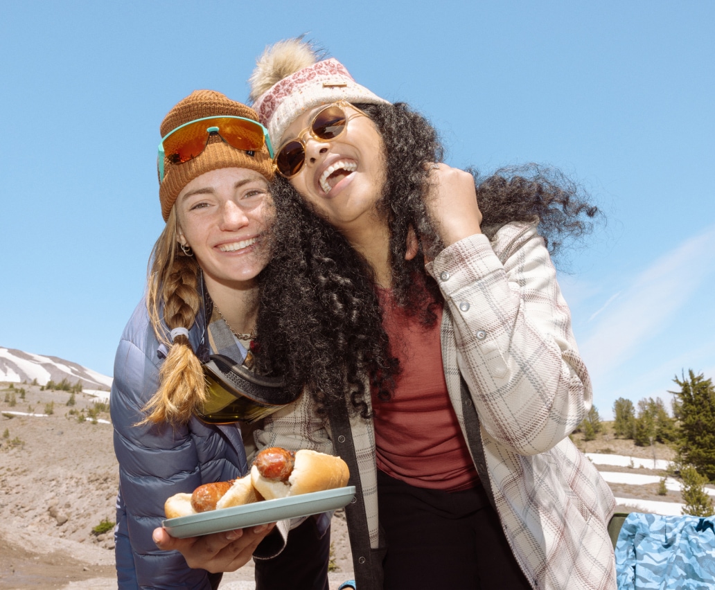 Campers smiling while sharing a meal.