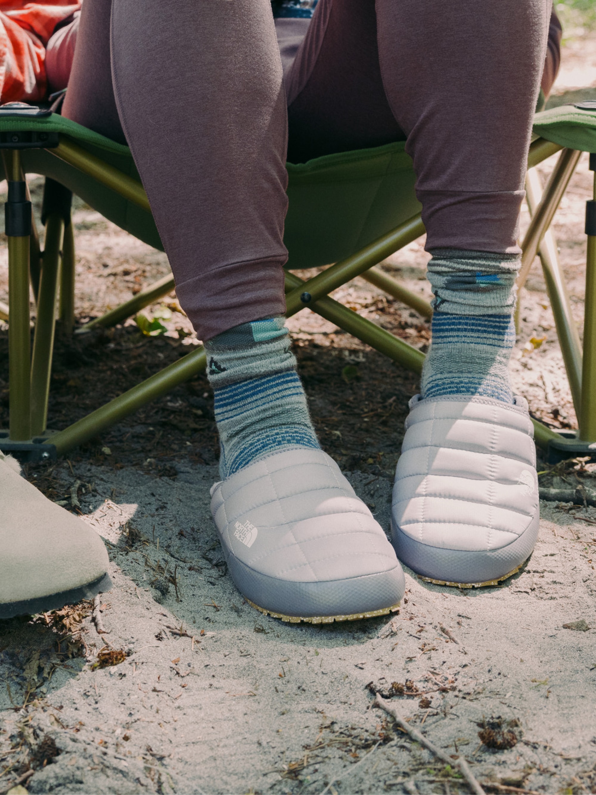 A camper enjoying downtime at their campsite in a pair of North Face slippers.