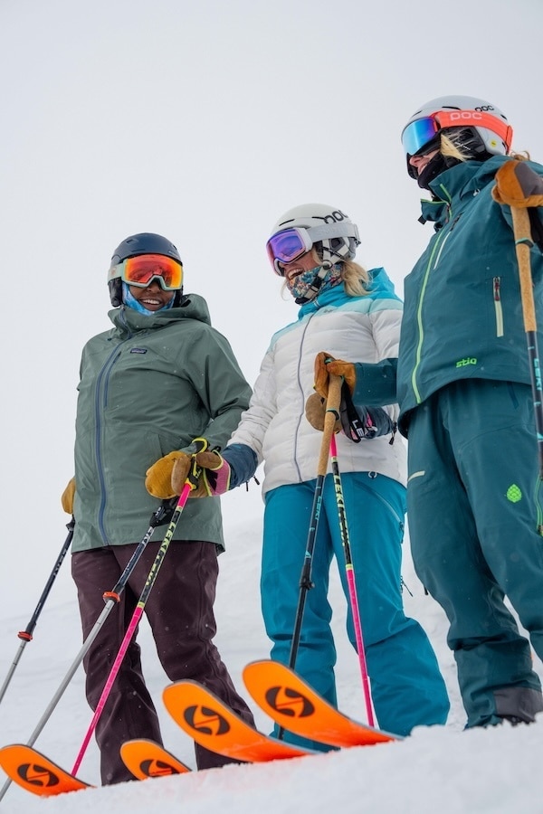 Three skiers stand in a row.