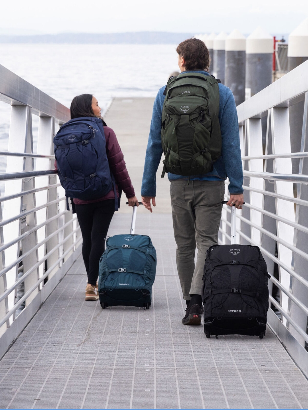 Travelers wheeling their luggage on a dock.