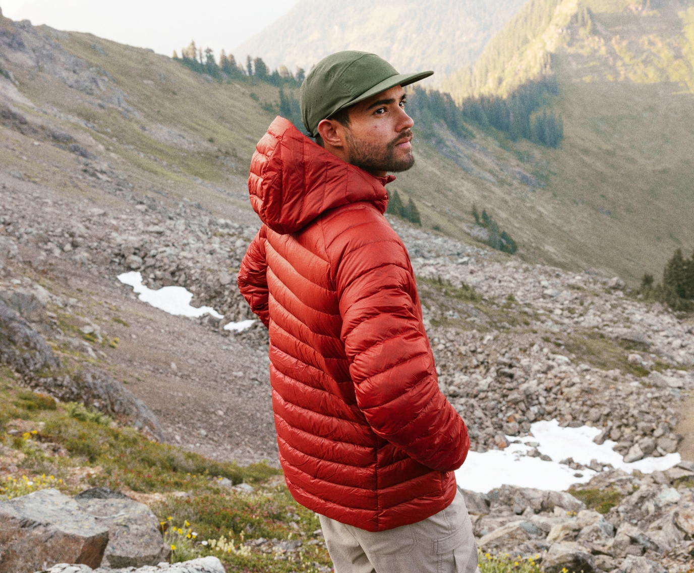 A person in a puffy jacket looking out over a mountain range.