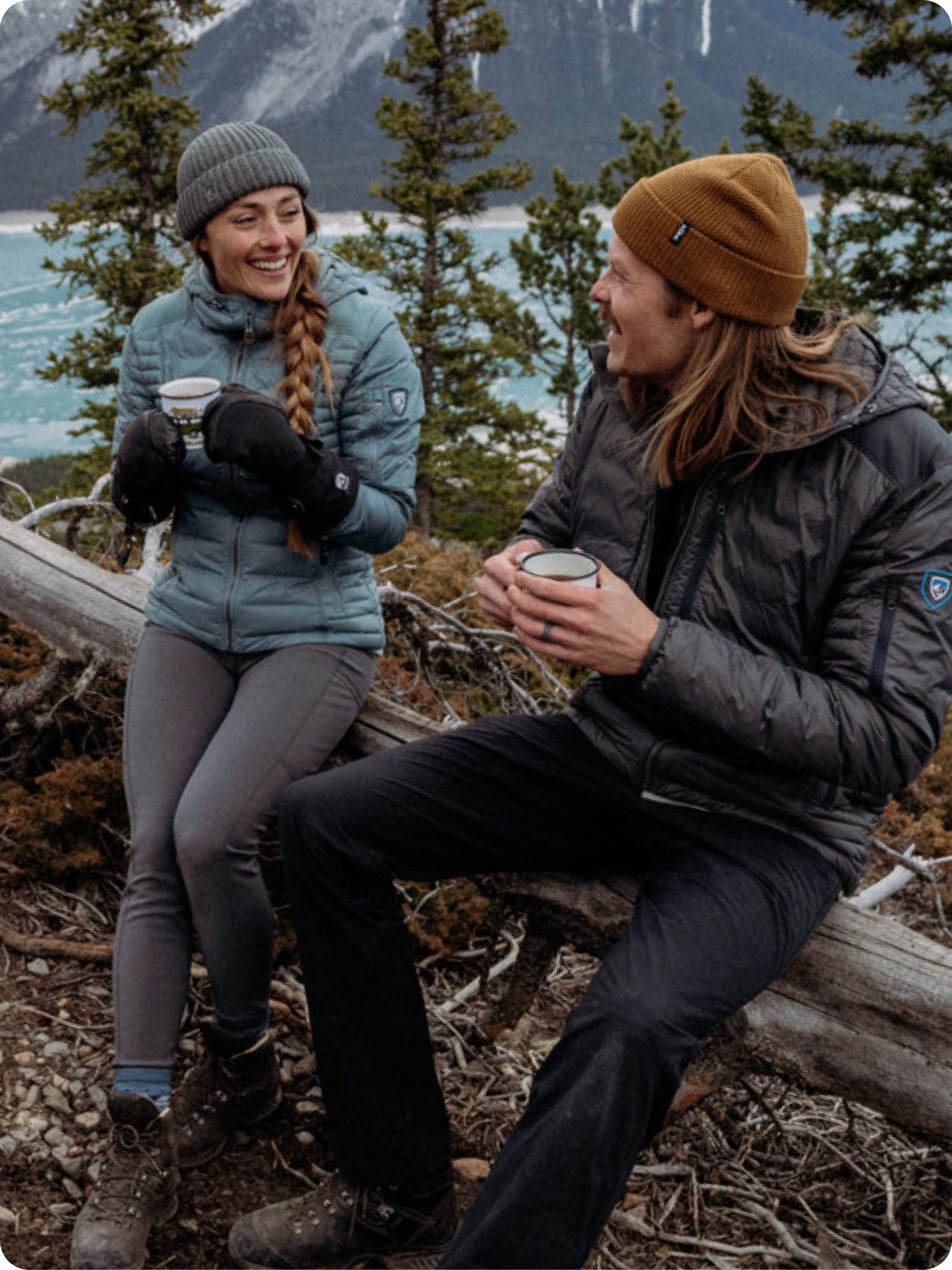 Two people enjoy warm beverages in their Kuhl jackets.