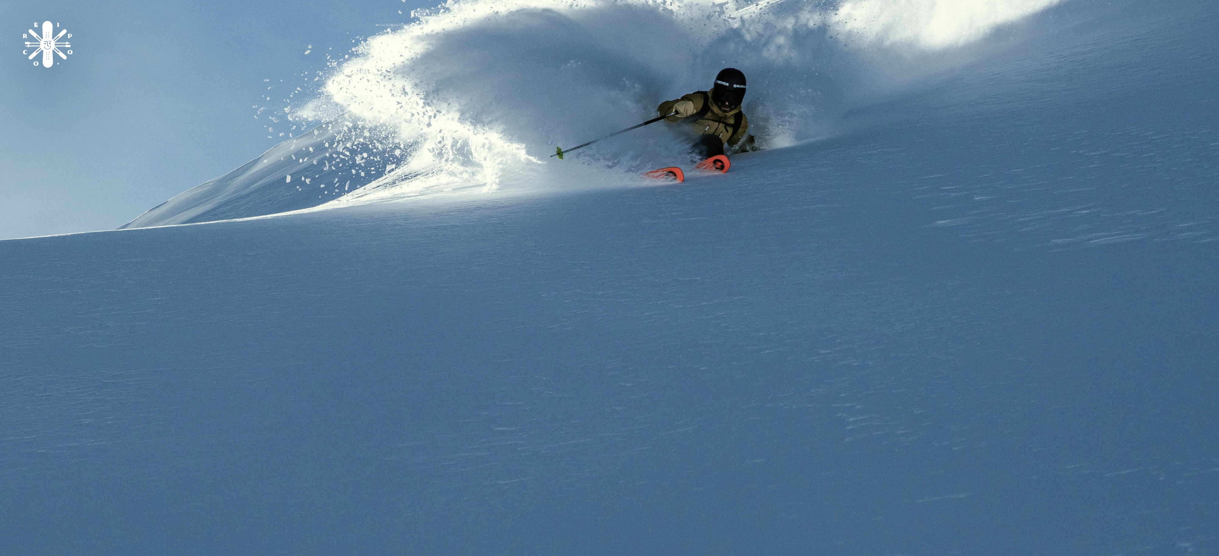 A skier carves through the snow.