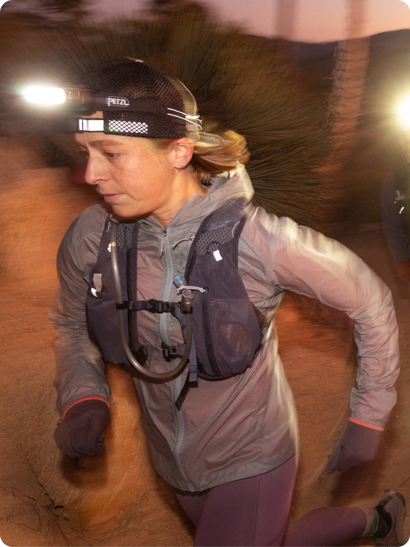 A runner wears a Petzl headlamp and a hydration vest.