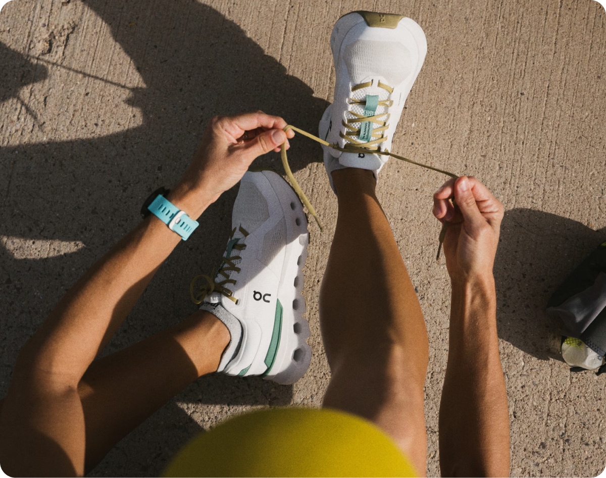 A person lacing up their On shoes before taking a walk.