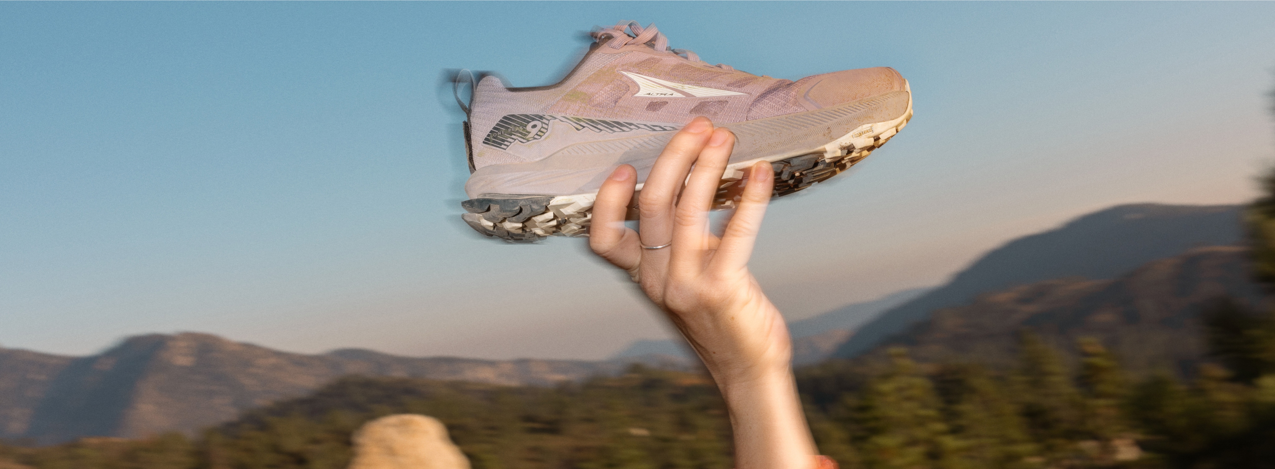 A person holds up the Altra Lone Peak 9 shoe for the camera.