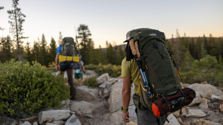 Two people hike over a rocky trail carrying backpacks