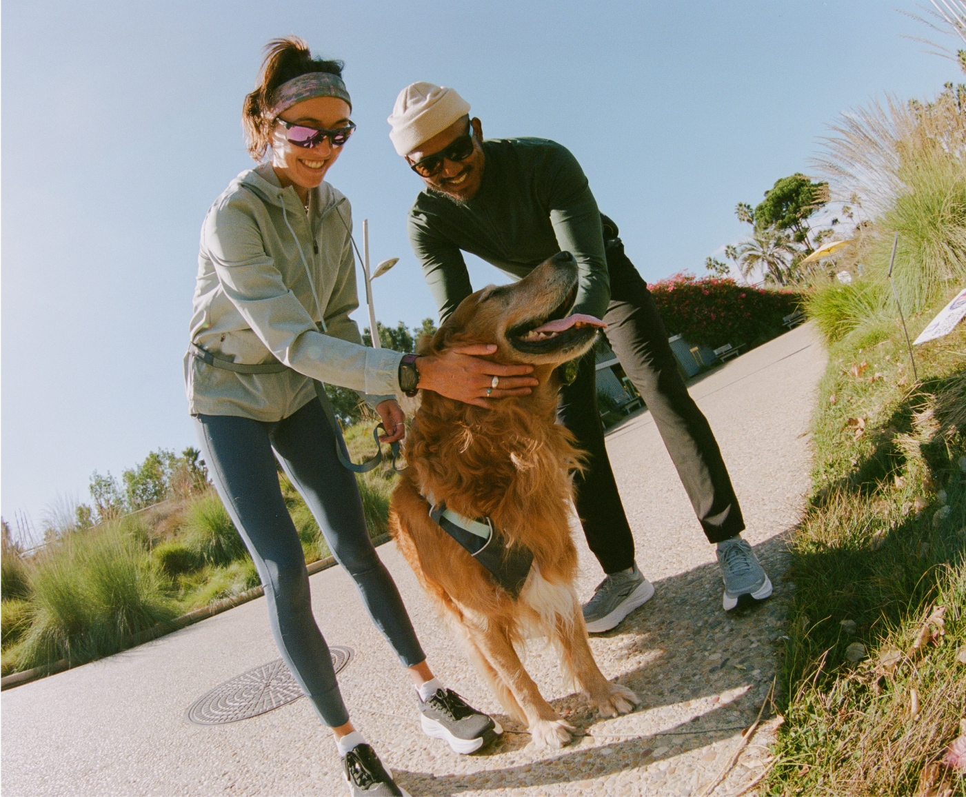 Two runners stop to give a few pets to a very good pup.