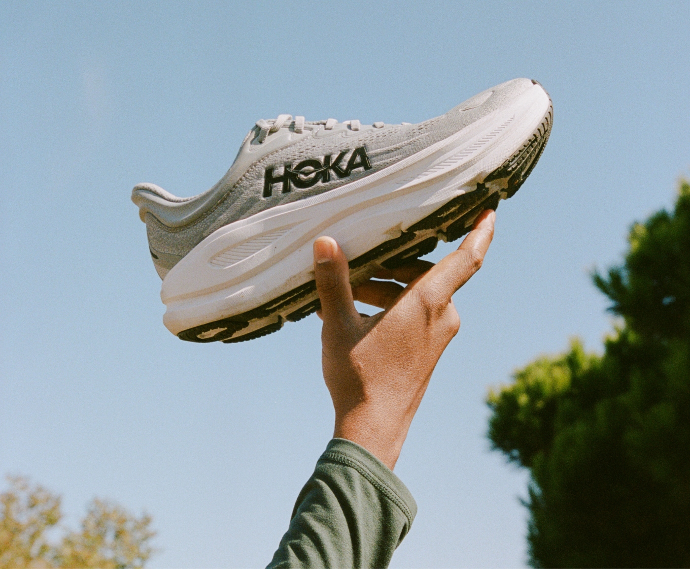 A person holds up a HOKA Bondi 9 for the camera.