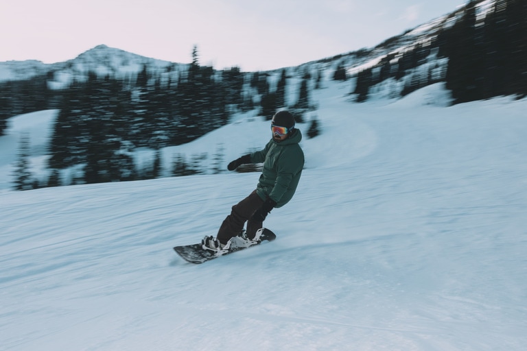 A snowboarder cruises down the slopes.