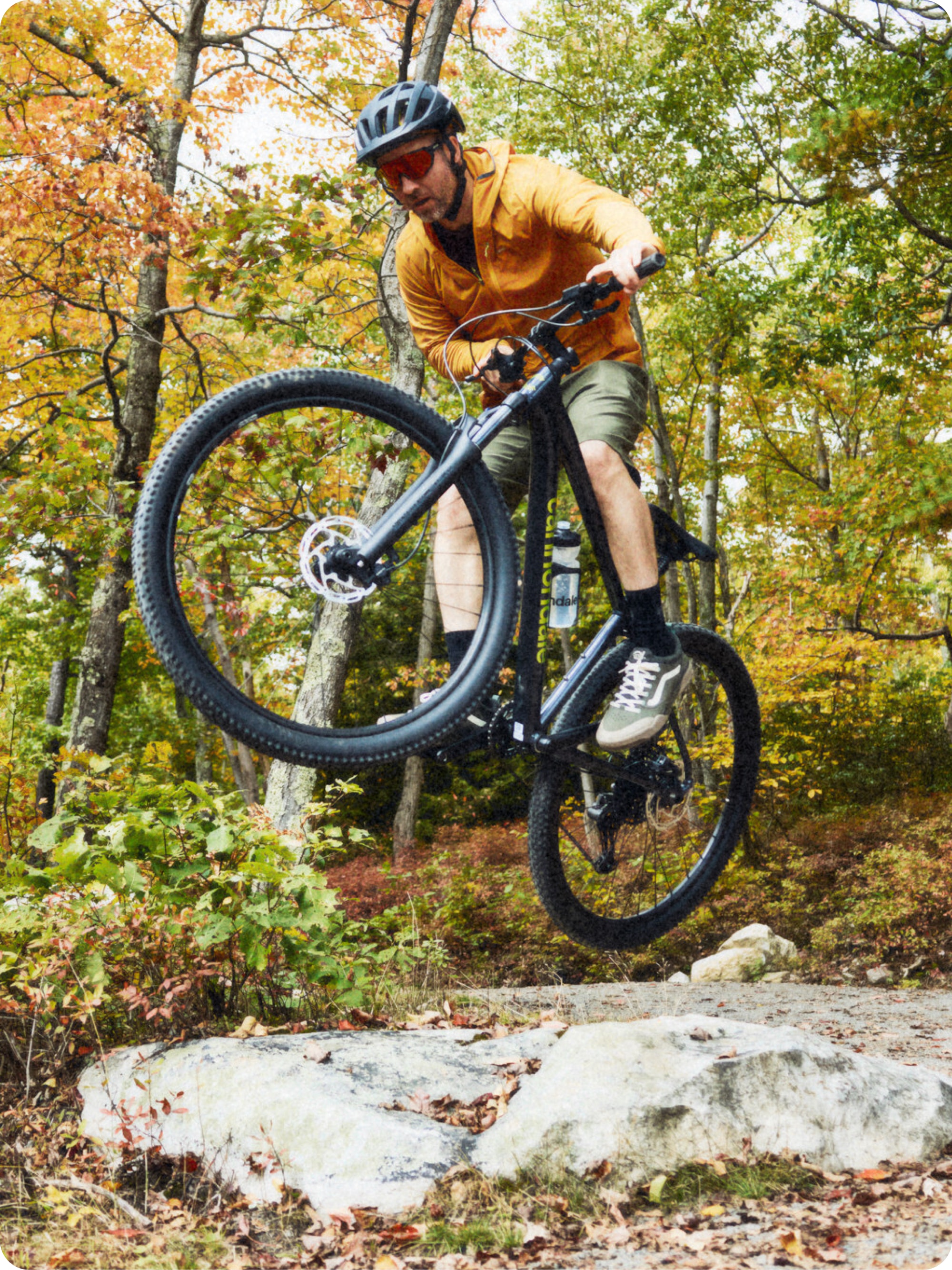 A person jumps over a rock on their mountain bike.