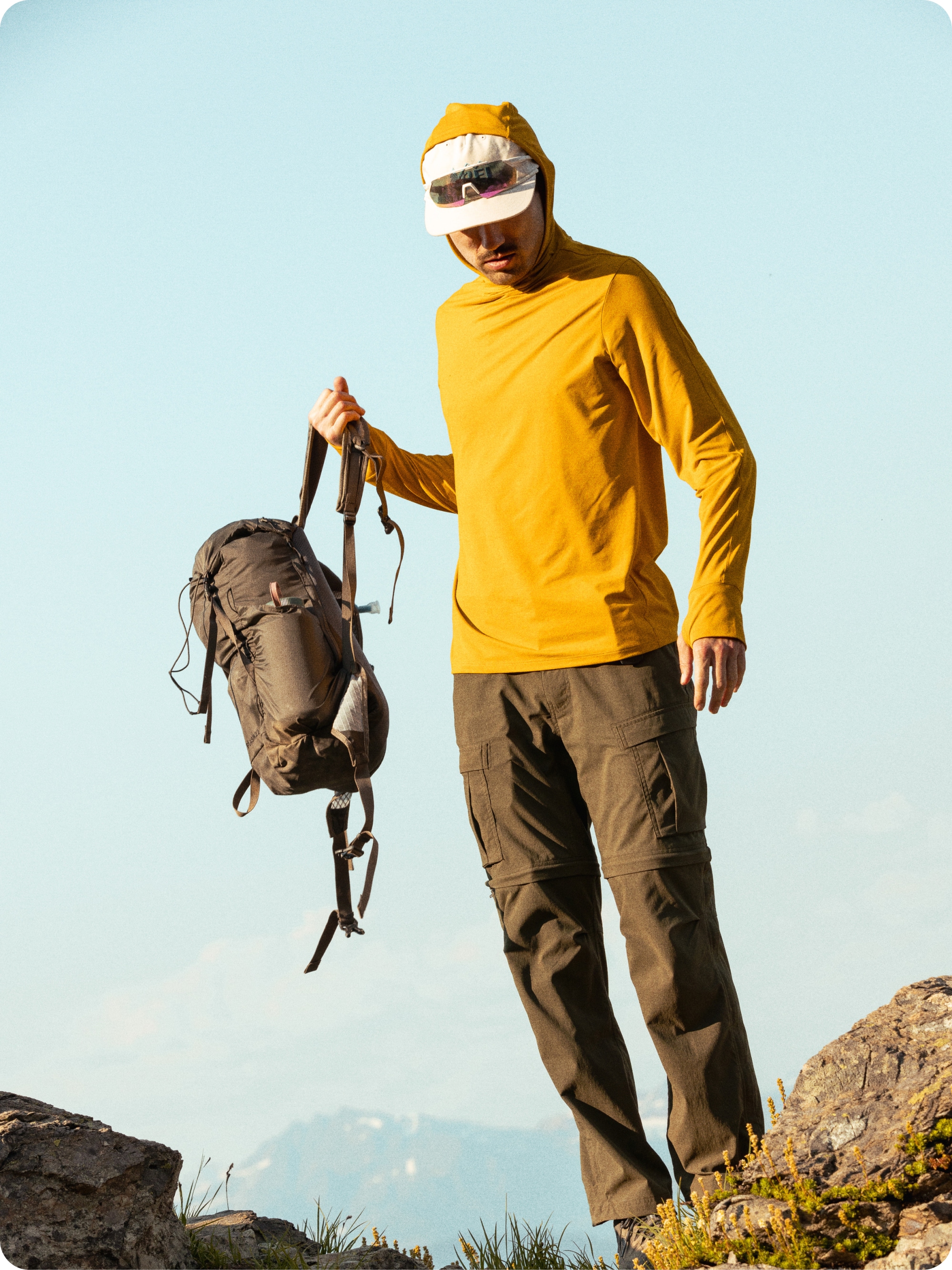 A hiker pulls their hiking pack on.