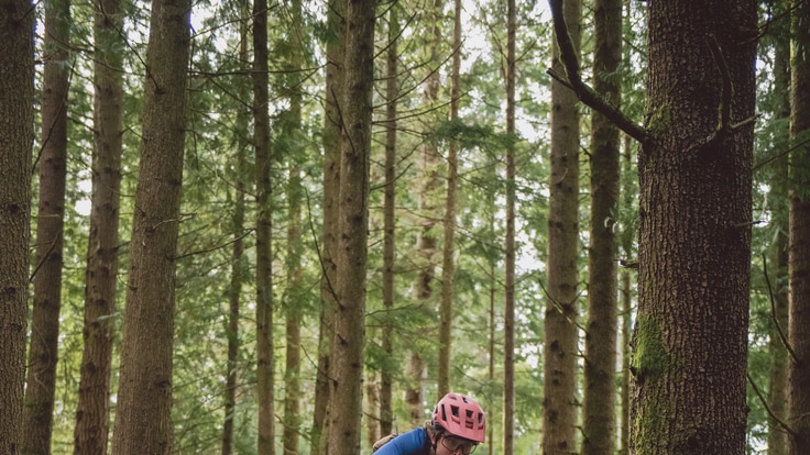 A person riding a mountain bike hits a dirt jump and is shown in air.