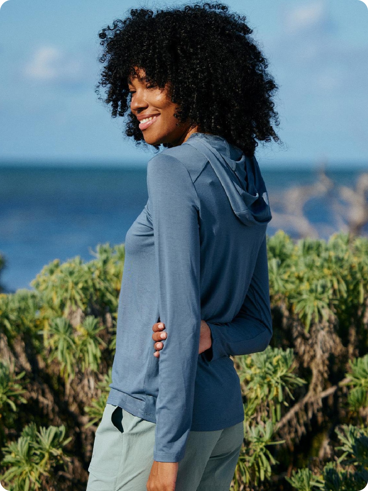 A person smiles for the camera in their Free Fly hoodie.