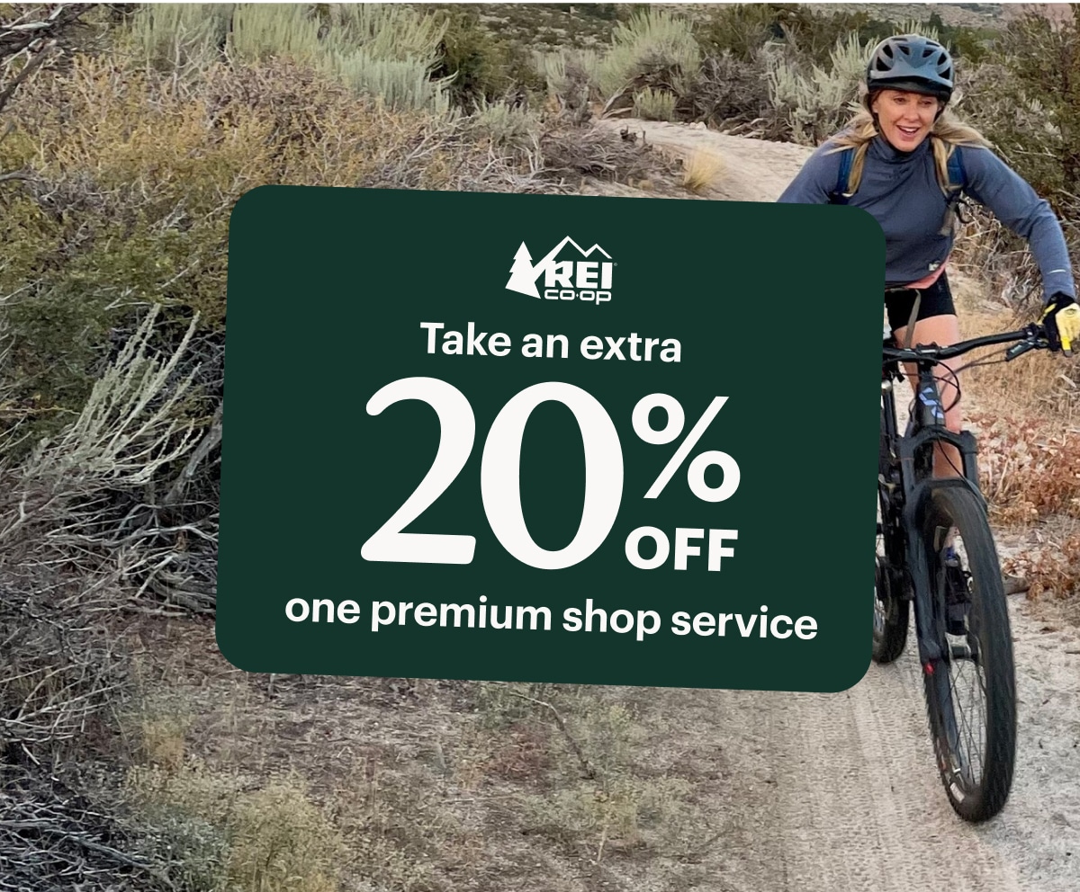 A member coupon for an extra 20 percent off one premium shop service over an image of a person biking through a trail.