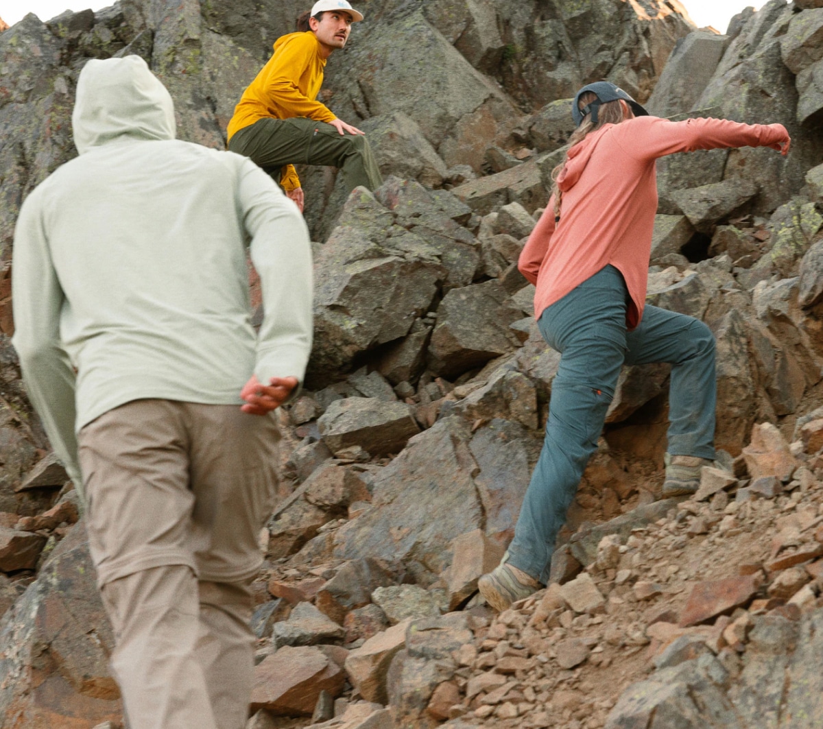 Three people climb up a very rocky path.