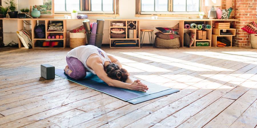 A yoga practitioner on a yoga mat with a yoga block nearby.