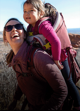 A person carries a child in the Deuter Kid Comfort Child Carrier