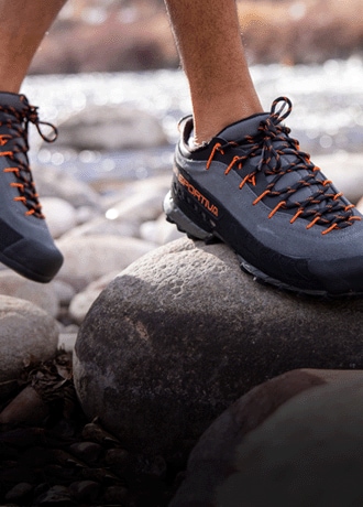 A person wears the La Sportiva TX 4 approach shoe and steps on a rock