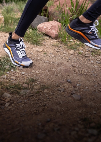 A person wears the The North Face VECTIV Infinite Trail-Running Shoe and steps on a rock