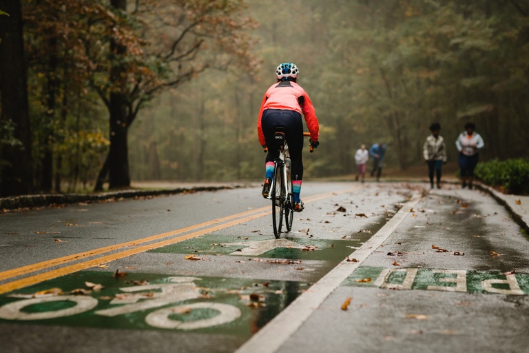 person biking on a wet road wearing bike pants and a rain jacket