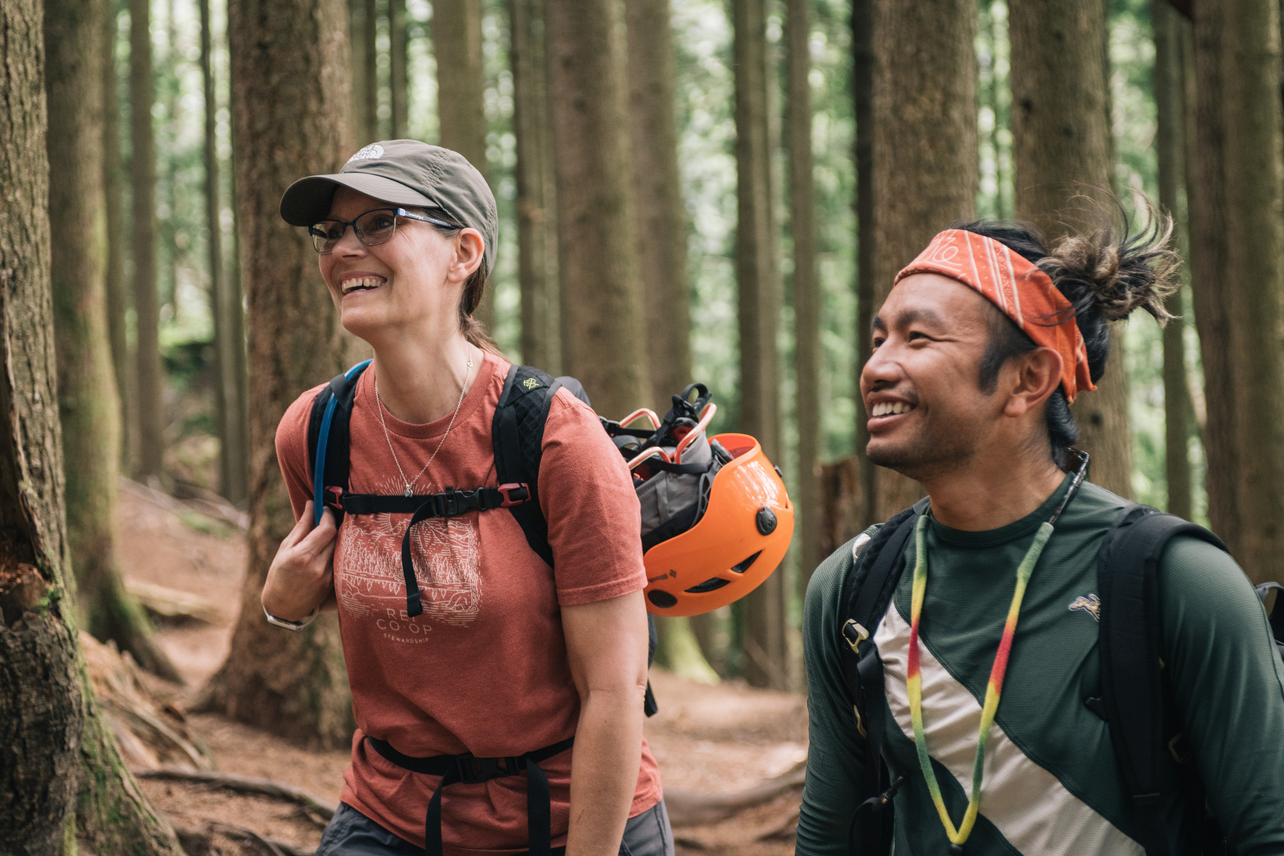 Two climbers hiking their gear through a forest.