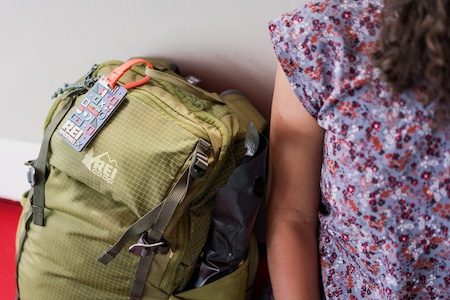 Woman sits next to her travel pack with id tag