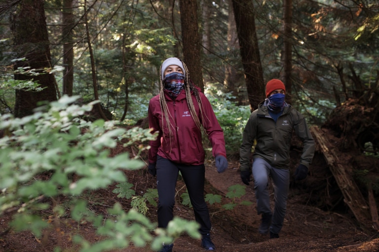 Two people hike through a forest.