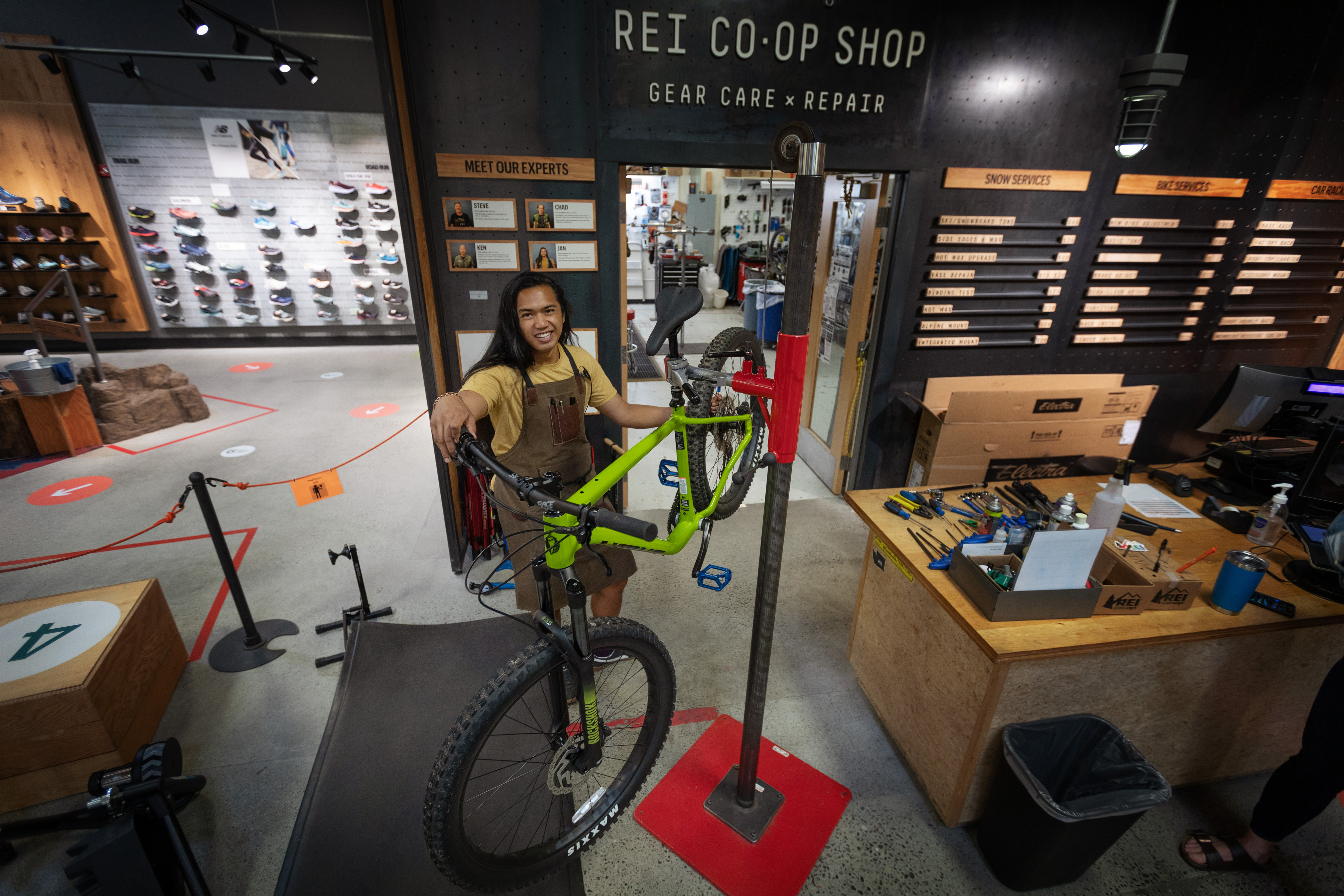 REI employee posing with a bike in front of the bike shop