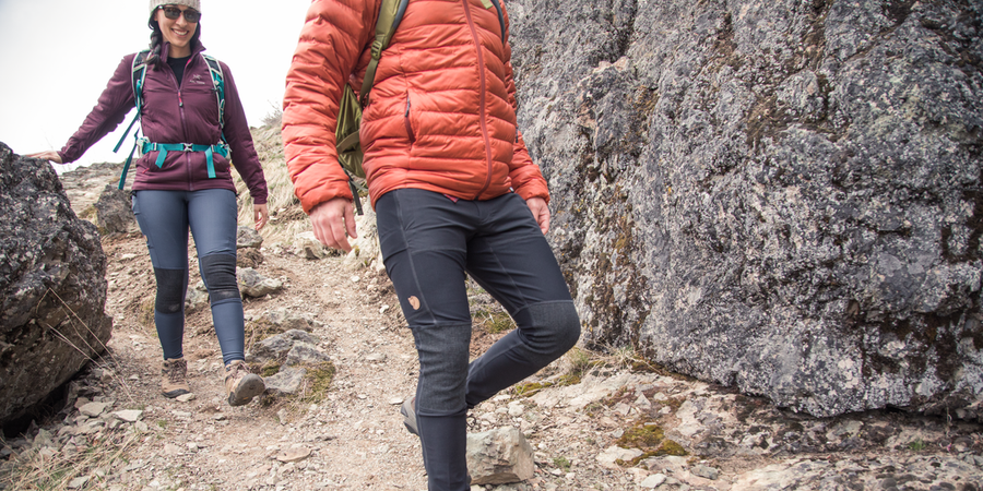 Two hikers wearing Fjallraven Abisko Trekking Tights hike through rocky terrain.