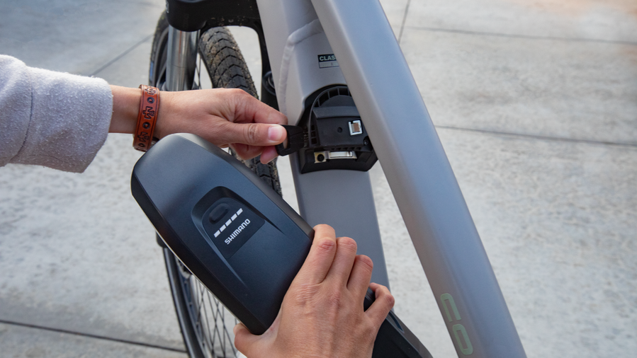 A person removes the battery from an electric bike