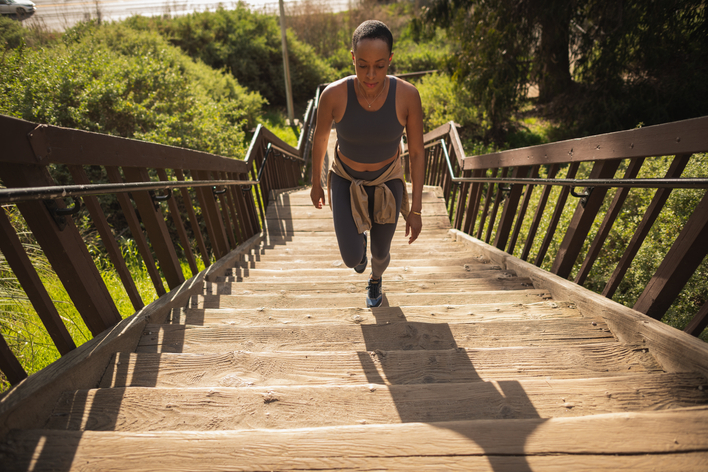 A person walks up wooden stairs in a green space.