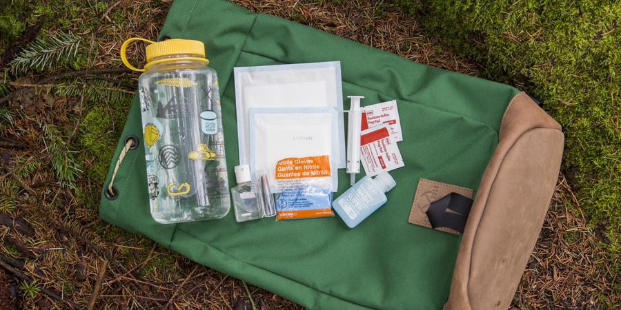 A collection of first-aid materials on a backpack laying on the ground.