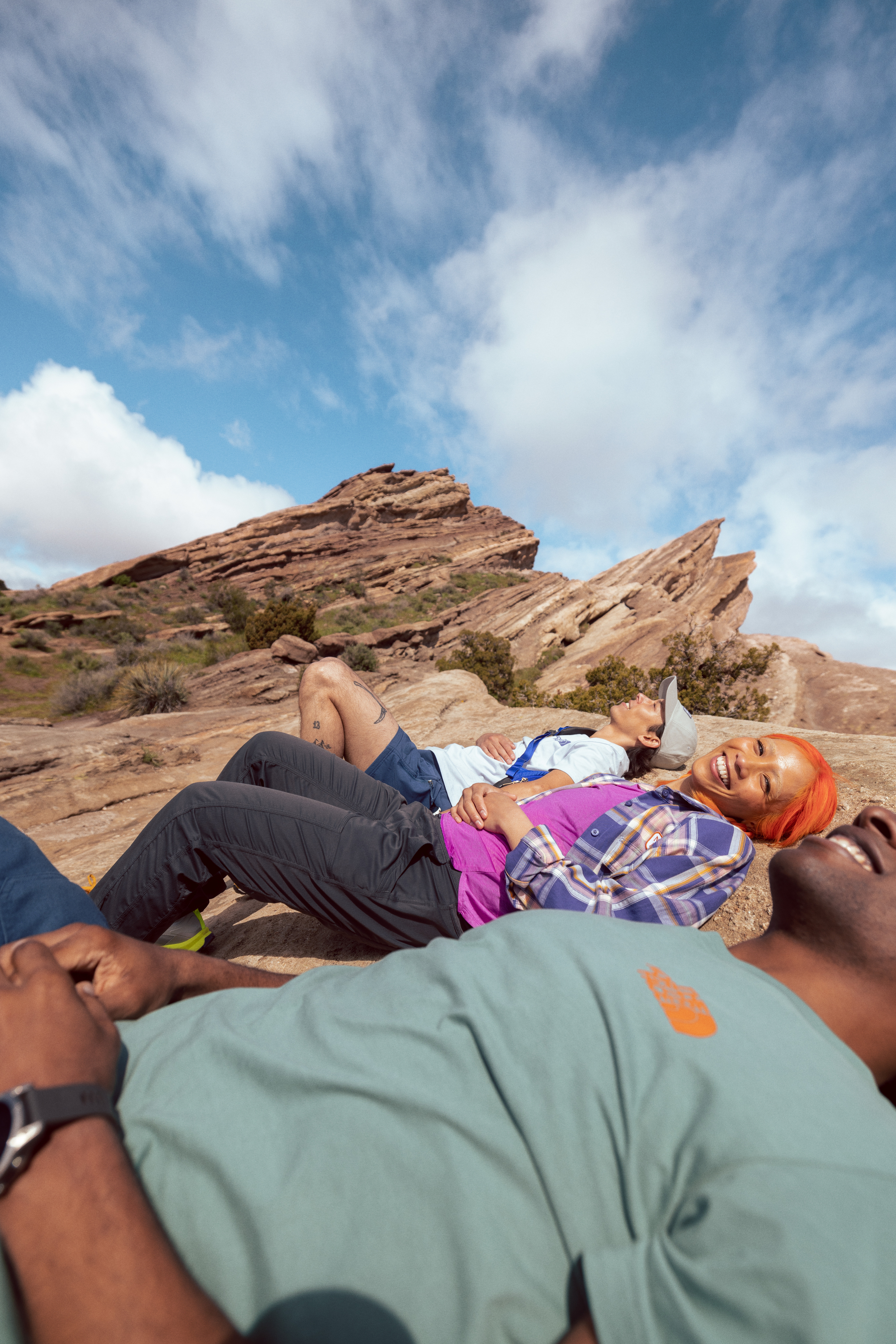 Three people wearing hiking gear recline on a mountain slope.