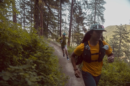 Two trail runners make there way through the trees.