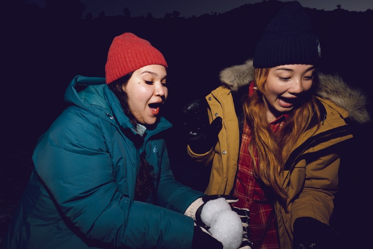 Two people play with snowballs in the dark.