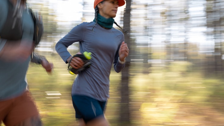 A person runs carrying a handheld water bottle