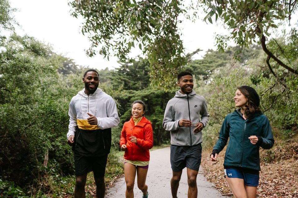 Group running through wooded area, paved trail.