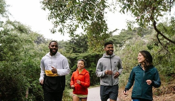 Group running through wooded area, paved trail.