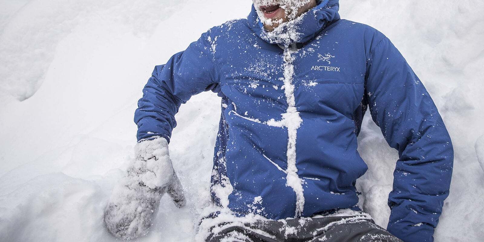 Close up of someone that has fallen in the snow and is laughing about it.Woman puts on shell over fleece jacket.