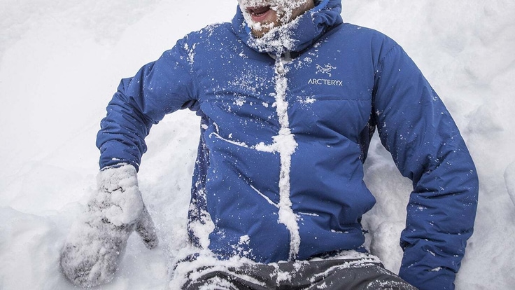 Close up of someone that has fallen in the snow and is laughing about it.