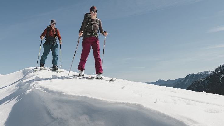 two backcountry skiers on a steep snowy ridge