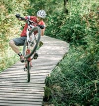 a mountain biker performing a wheelie to practice and perfect their downhill technique