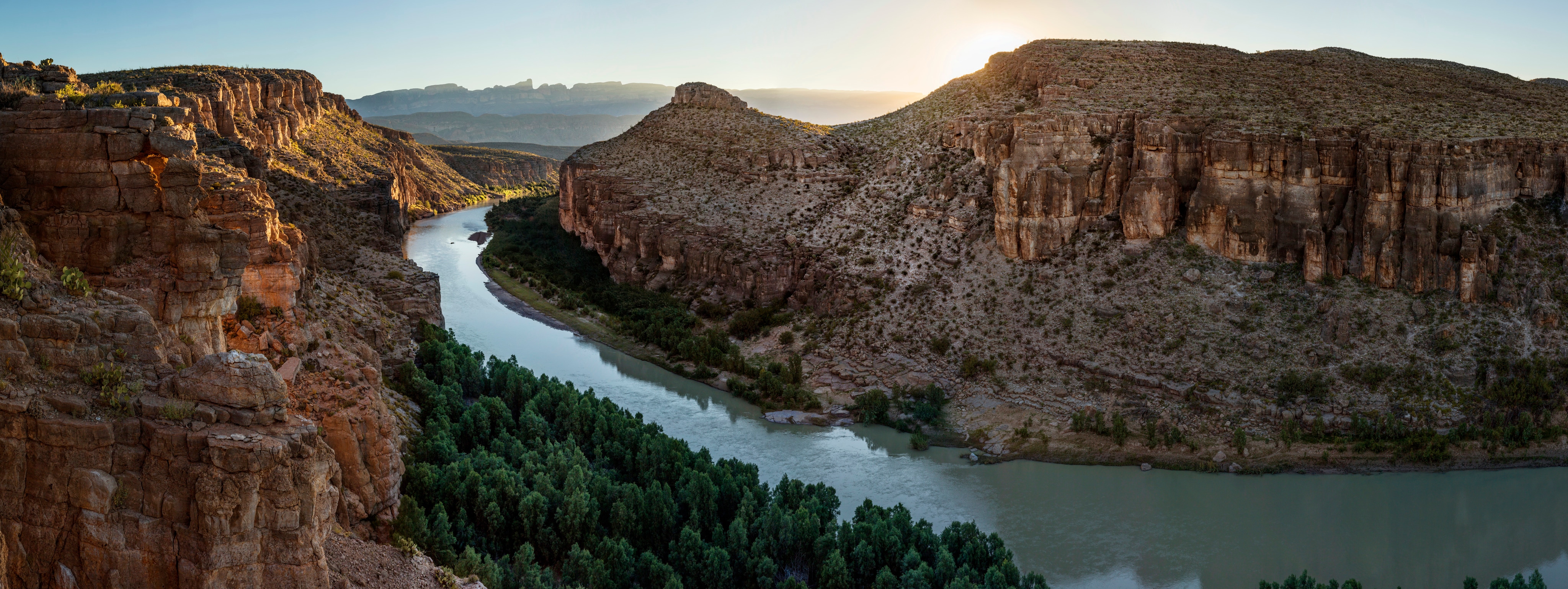 A river winds through a vast canyon at sunrise