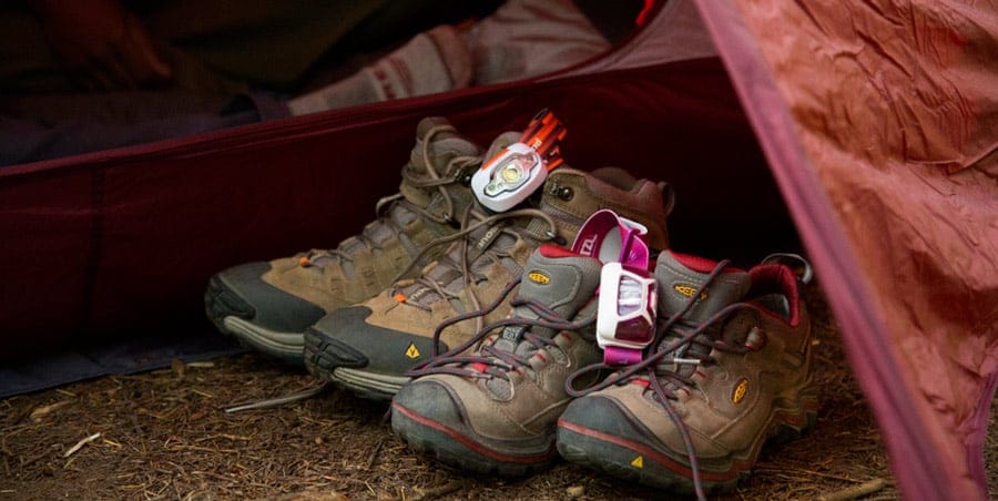 a camper's boots and headlamp placed outside their tent