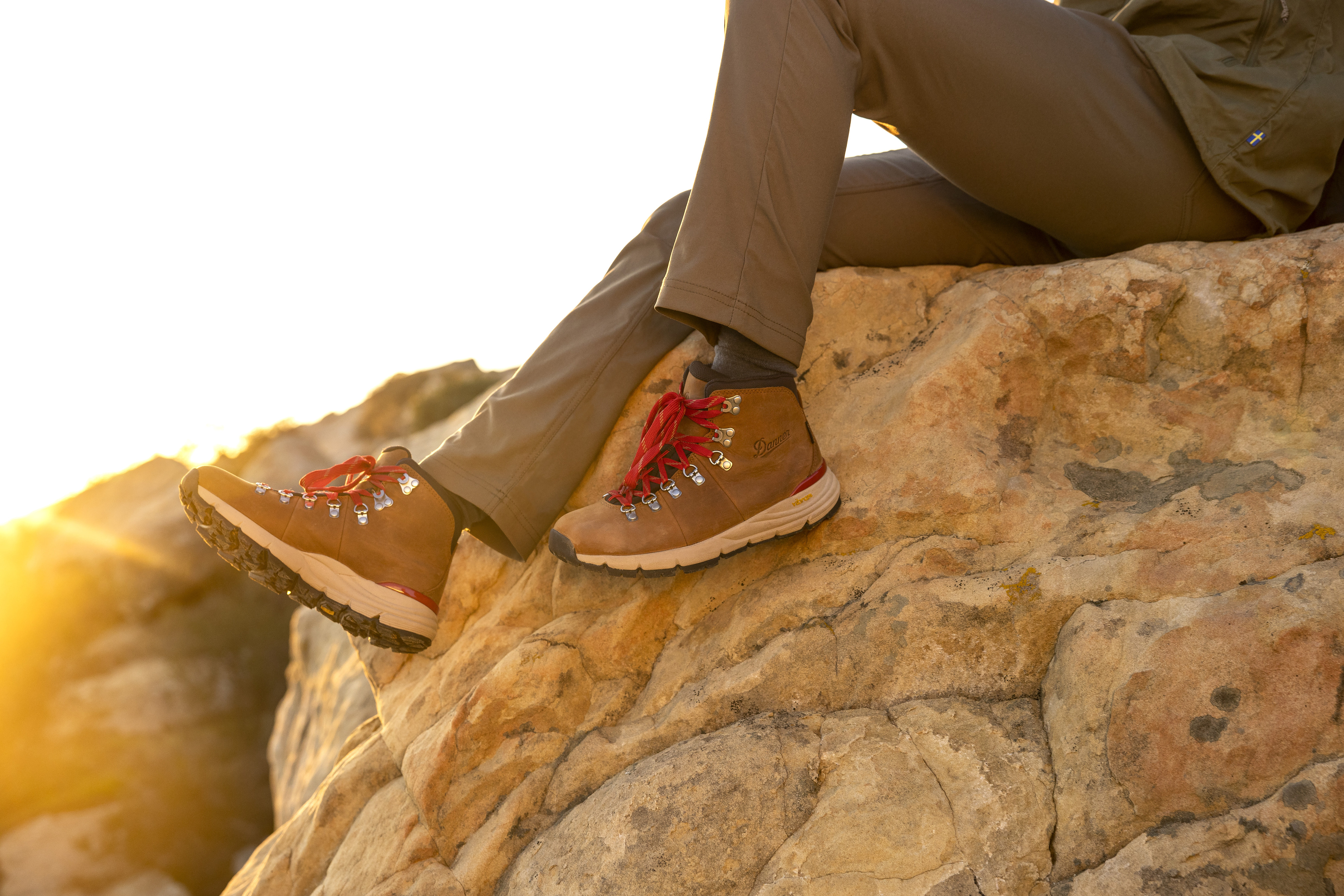 Hiker wearing Danner 600 boots with the red laces sits on a rock